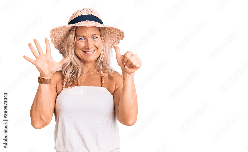 Middle age fit blonde woman wearing summer hat showing and pointing up with fingers number six while smiling confident and happy. Middle age fit blonde woman wearing summer hat showing and pointing up with fingers number six while smiling confident and happy.