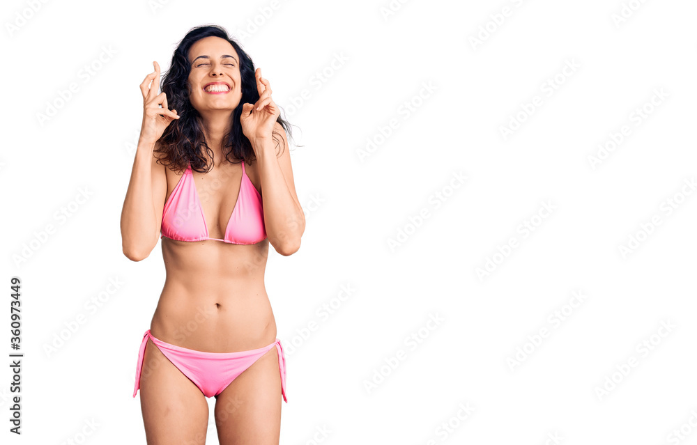 Young beautiful hispanic woman wearing bikini gesturing finger crossed smiling with hope and eyes closed. luck and superstitious concept. Young beautiful hispanic woman wearing bikini gesturing finger crossed smiling with hope and eyes closed. luck and superstitious concept.