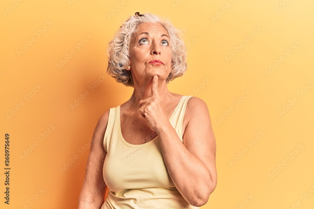 Senior grey-haired woman wearing casual clothes thinking concentrated about doubt with finger on chin and looking up wondering Senior grey-haired woman wearing casual clothes thinking concentrated about doubt with finger on chin and looking up wondering