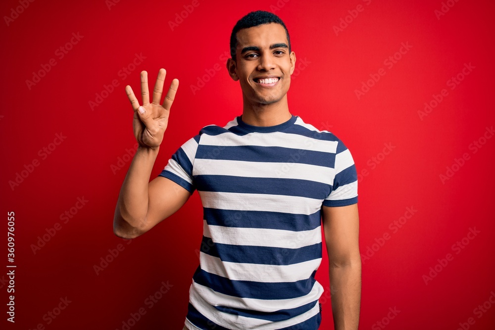 Handsome african american man wearing casual striped t-shirt standing over red background showing and pointing up with fingers number four while smiling confident and happy. Handsome african american man wearing casual striped t-shirt standing over red background showing and pointing up with fingers number four while smiling confident and happy.