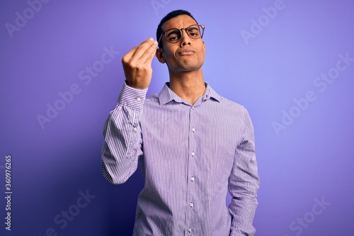 Handsome african american man wearing striped shirt and glasses over purple background Doing Italian gesture with hand and fingers confident expression