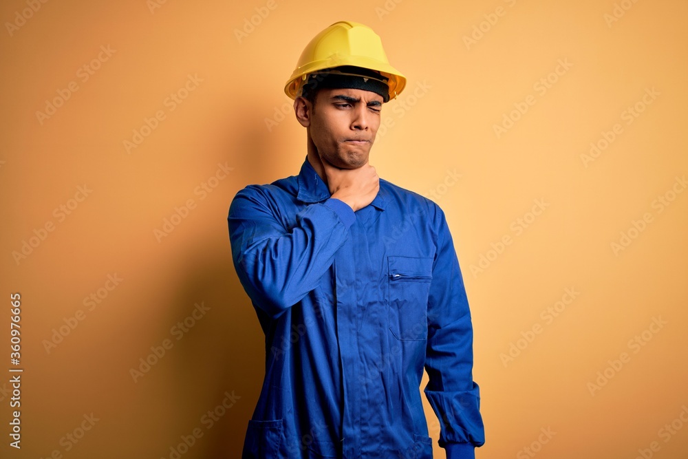 Young handsome african american worker man wearing blue uniform and security helmet Touching painful neck, sore throat for flu, clod and infection