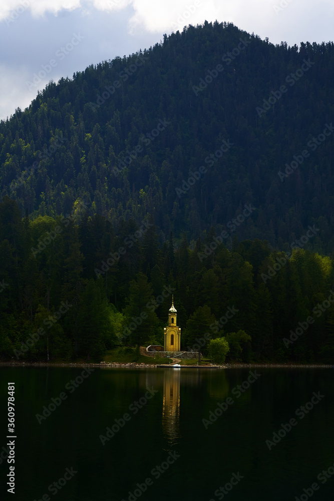 Fototapeta premium chapel built in a wooded area on the lake, the concept of the unity of nature and religion. holy place and faith