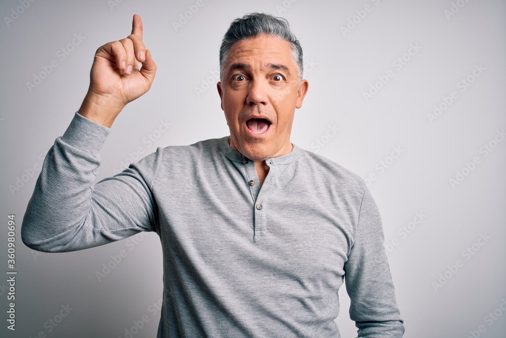 Middle age handsome grey-haired man wearing casual t-shirt over white background pointing finger up with successful idea. Exited and happy. Number one. Middle age handsome grey-haired man wearing casual t-shirt over white background pointing finger up with successful idea. Exited and happy. Number one.