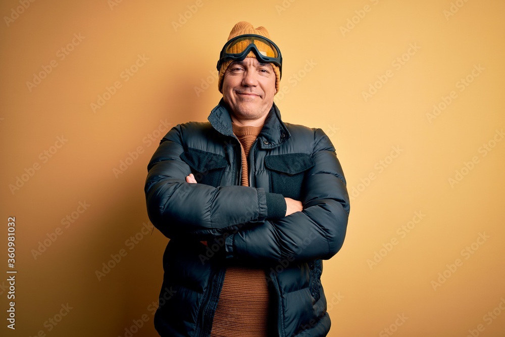 Middle age handsome grey-haired skier man on vacation wearing ski goggles happy face smiling with crossed arms looking at the camera. Positive person. Middle age handsome grey-haired skier man on vacation wearing ski goggles happy face smiling with crossed arms looking at the camera. Positive person.