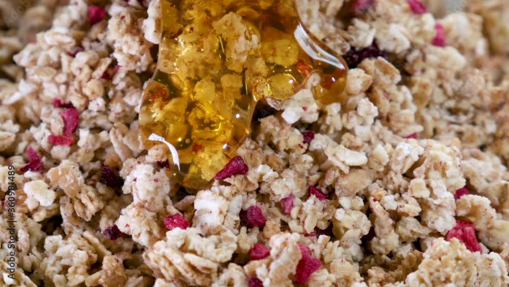 Golden, liquid honey slowly flows over organic crispy muesli with fruits. Golden, liquid honey slowly flows over organic crispy muesli with fruits.