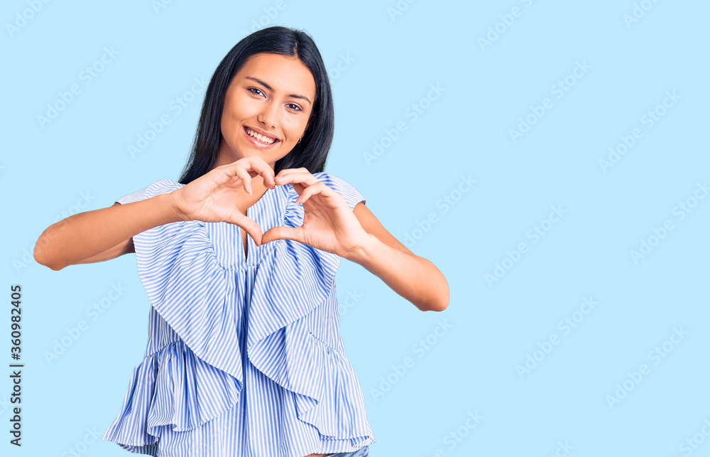 Young beautiful latin girl wearing casual clothes smiling in love doing heart symbol shape with hands. romantic concept. Young beautiful latin girl wearing casual clothes smiling in love doing heart symbol shape with hands. romantic concept.