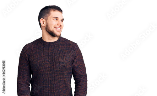 Young handsome man wearing casual sweater looking away to side with smile on face, natural expression. laughing confident. © Krakenimages.com