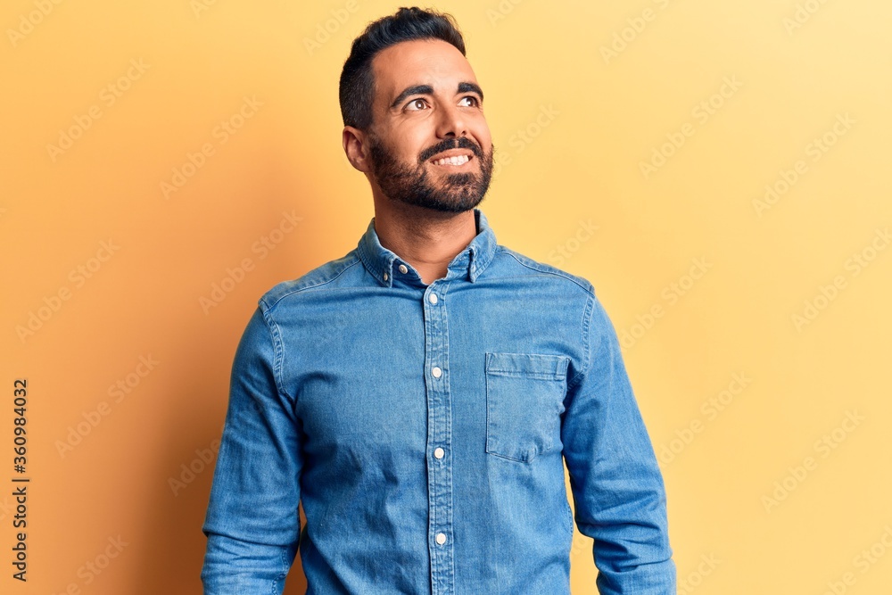Young hispanic man wearing casual clothes looking away to side with smile on face, natural expression. laughing confident. Young hispanic man wearing casual clothes looking away to side with smile on face, natural expression. laughing confident.