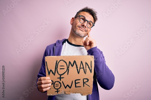 Young handsome man asking for women rights holding banner with woman power message serious face thinking about question, very confused idea