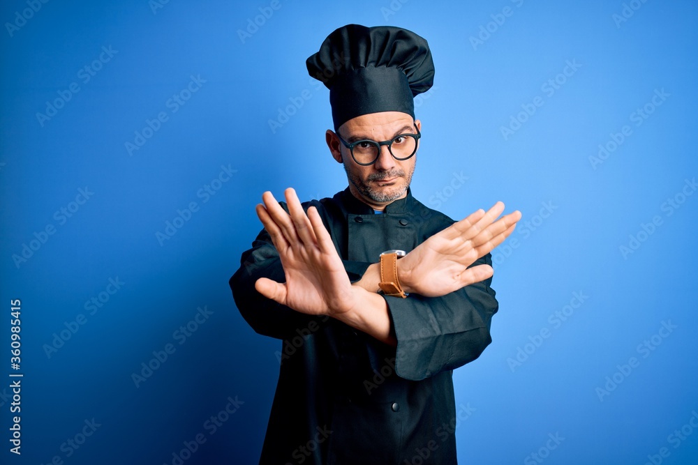 Young handsome chef man wearing cooker uniform and hat over isolated blue background Rejection expression crossing arms doing negative sign, angry face Young handsome chef man wearing cooker uniform and hat over isolated blue background Rejection expression crossing arms doing negative sign, angry face
