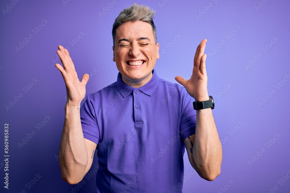 Young handsome modern man wearing casual purple t-shirt over isolated background celebrating mad and crazy for success with arms raised and closed eyes screaming excited. Winner concept Young handsome modern man wearing casual purple t-shirt over isolated background celebrating mad and crazy for success with arms raised and closed eyes screaming excited. Winner concept