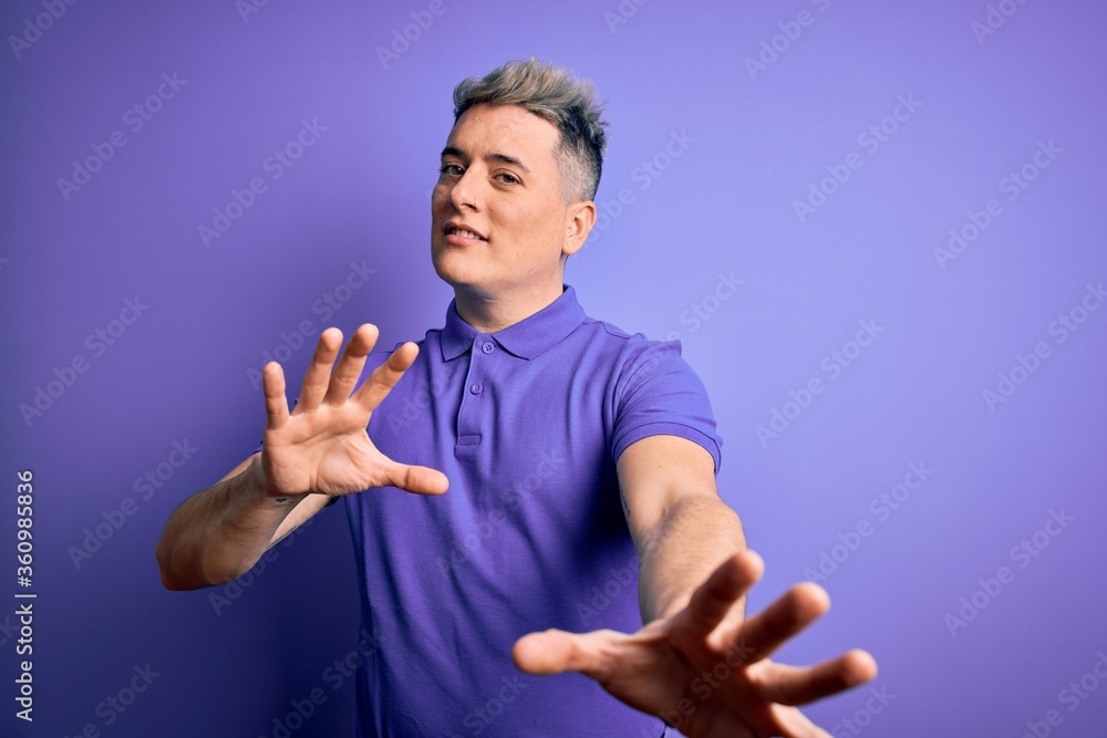 Naklejka premium Young handsome modern man wearing casual purple t-shirt over isolated background afraid and terrified with fear expression stop gesture with hands, shouting in shock. Panic concept.