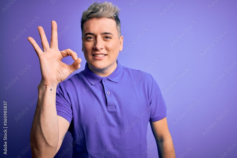 Young handsome modern man wearing casual purple t-shirt over isolated background smiling positive doing ok sign with hand and fingers. Successful expression. Young handsome modern man wearing casual purple t-shirt over isolated background smiling positive doing ok sign with hand and fingers. Successful expression.