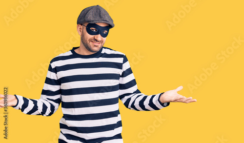Φωτογραφία Young handsome man wearing burglar mask smiling showing both hands open palms, p