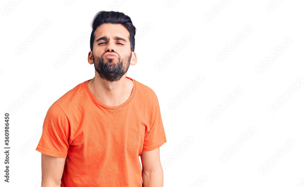 Young handsome man with beard wearing casual t-shirt looking at the camera blowing a kiss on air being lovely and sexy. love expression. Young handsome man with beard wearing casual t-shirt looking at the camera blowing a kiss on air being lovely and sexy. love expression.