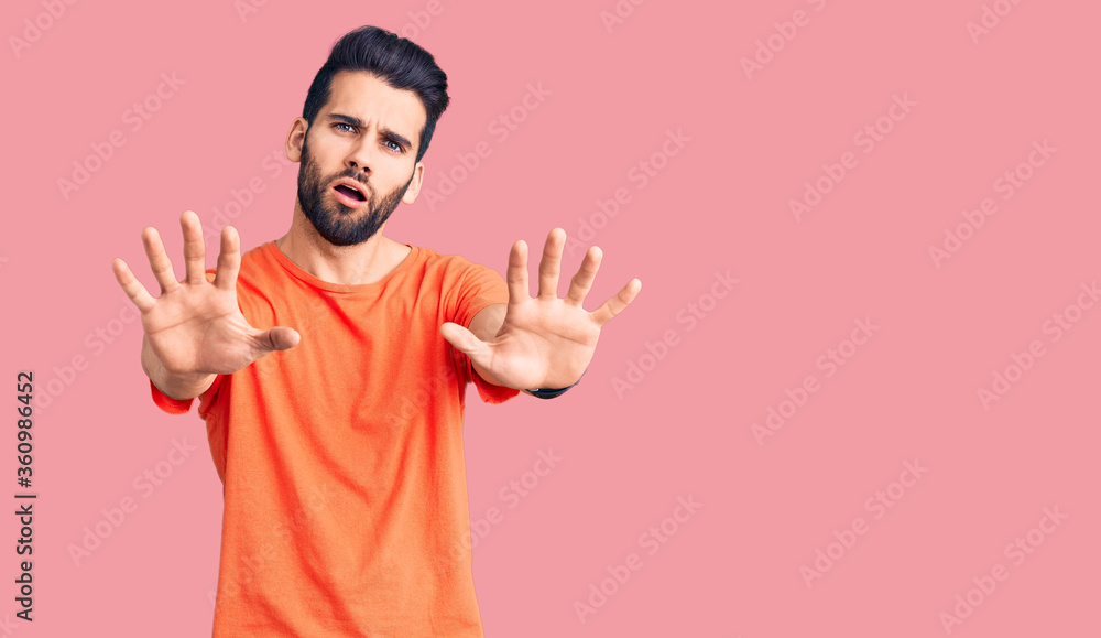 Young handsome man with beard wearing casual t-shirt doing stop gesture with hands palms, angry and frustration expression Young handsome man with beard wearing casual t-shirt doing stop gesture with hands palms, angry and frustration expression