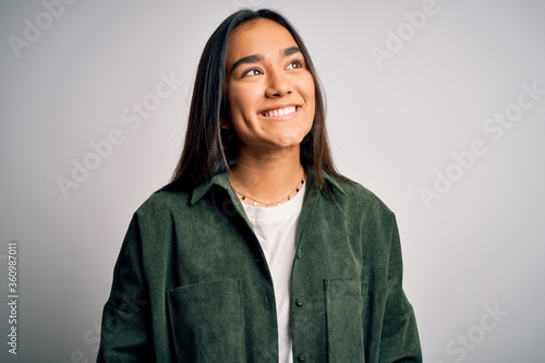 Obraz na plátně Young beautiful asian woman wearing casual shirt standing over isolated white background looking away to side with smile on face, natural expression