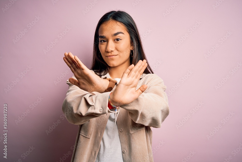 Young beautiful asian woman wearing casual shirt standing over pink background Rejection expression crossing arms doing negative sign, angry face Young beautiful asian woman wearing casual shirt standing over pink background Rejection expression crossing arms doing negative sign, angry face