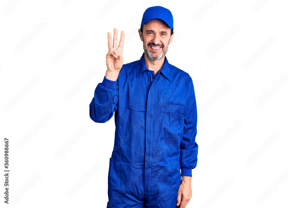 Middle age handsome man wearing mechanic uniform showing and pointing up with fingers number three while smiling confident and happy.