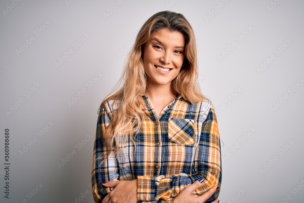 Young beautiful blonde woman wearing casual shirt standing over isolated white background happy face smiling with crossed arms looking at the camera. Positive person. Young beautiful blonde woman wearing casual shirt standing over isolated white background happy face smiling with crossed arms looking at the camera. Positive person.