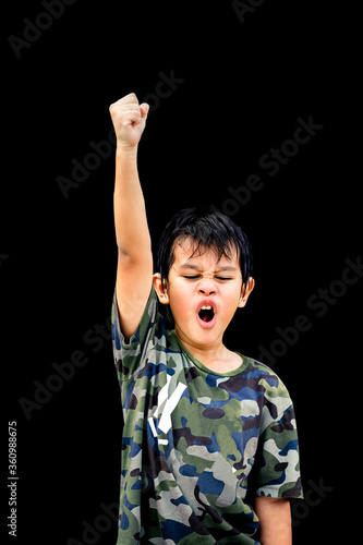 asian boy raising hand on black background ,Holding a fist above the head, The boy said he was fighting.asian ,people on isolated background.