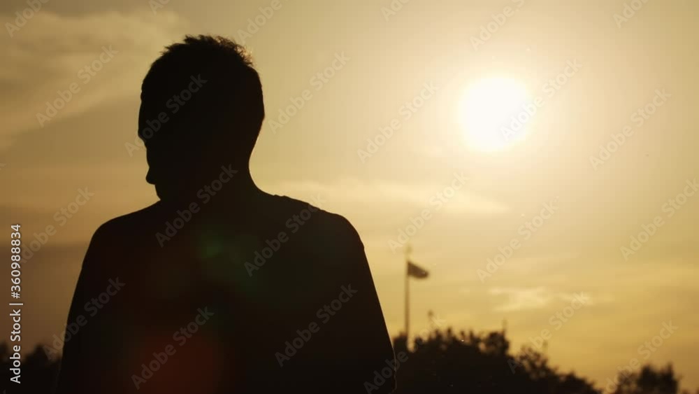 Silhouette of inspired person watching colorful sunset in open nature landscape. Back of man phoitographer taking pictures standing on hilltop viewpoint on summer evening. Silhouette of inspired person watching colorful sunset in open nature landscape. Back of man phoitographer taking pictures standing on hilltop viewpoint on summer evening.