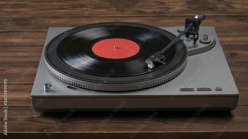 A red vinyl record player on a wooden table. A red vinyl record player on a wooden table.