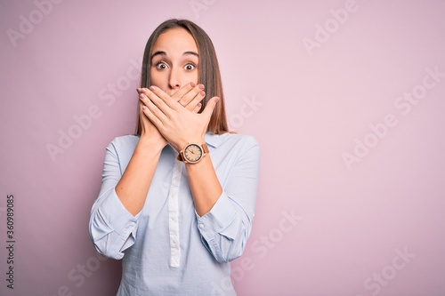 Young beautiful businesswoman wearing elegant shirt standing over isolated pink background shocked covering mouth with hands for mistake. Secret concept.