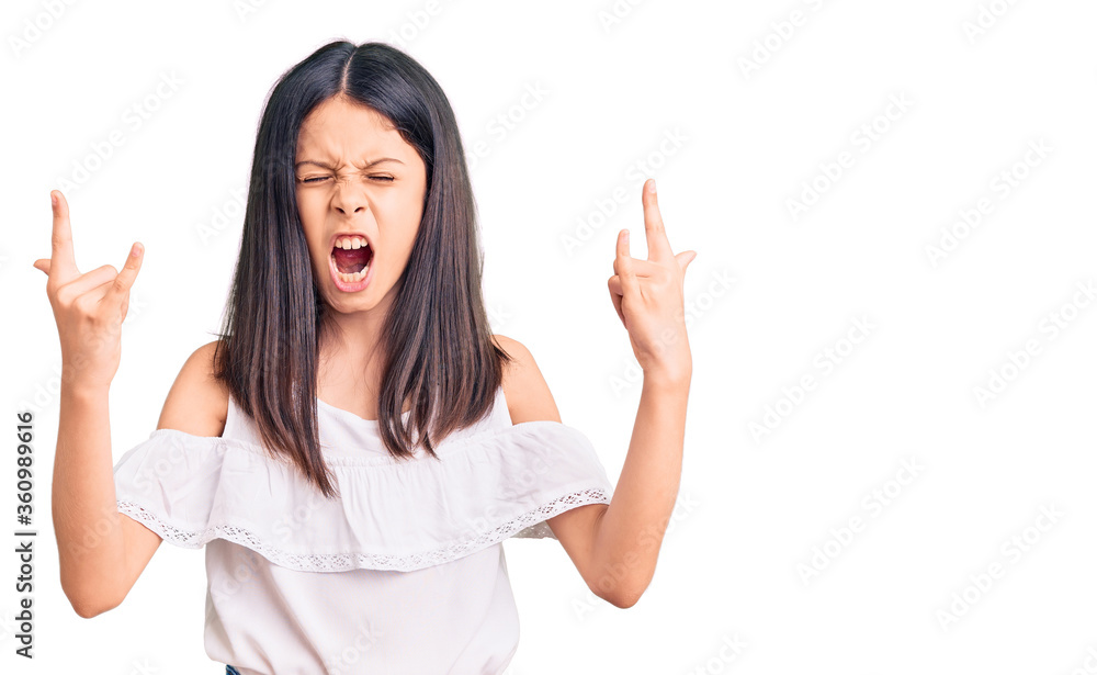 Beautiful child girl wearing casual clothes shouting with crazy expression doing rock symbol with hands up. music star. heavy concept. Beautiful child girl wearing casual clothes shouting with crazy expression doing rock symbol with hands up. music star. heavy concept.