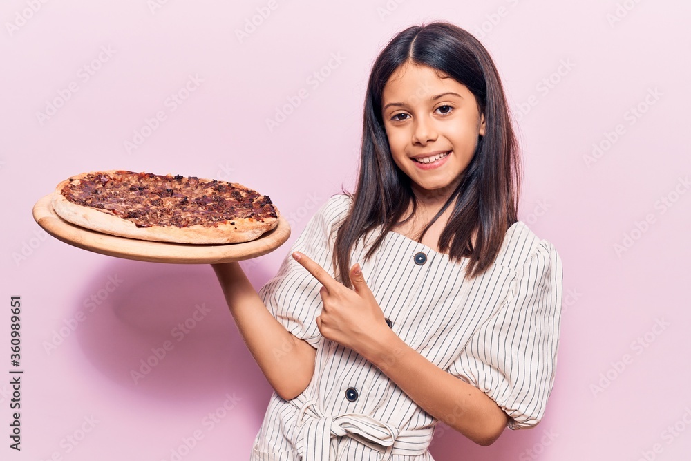 Beautiful child girl holding italian pizza smiling happy pointing with hand and finger Beautiful child girl holding italian pizza smiling happy pointing with hand and finger