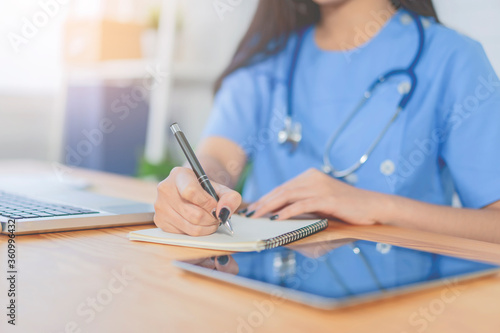 Asian female beautiful doctor working with digital tablet surgeon made video call support in an ER hospital, OR,operating theatre, surgical room, healthcare and medical concept, stethoscope on neck