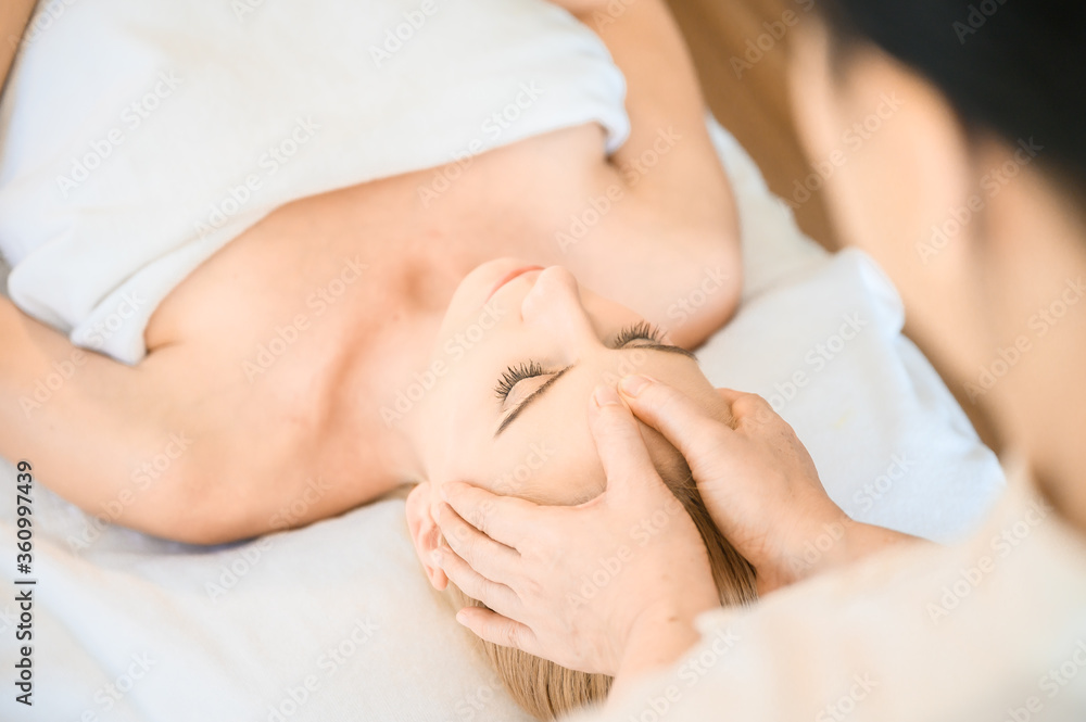Beautiful woman receiving head and facial massage in spa salon. Concept of body health care and traditional thai massage relax Beautiful woman receiving head and facial massage in spa salon. Concept of body health care and traditional thai massage relax