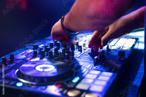 DJ hands mix music on a mixing Board in a nightclub
