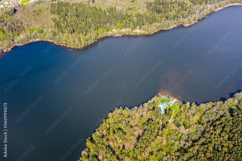 aerial view of blue lake and green forests on a sunny summer day. birds eyes view