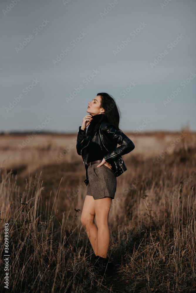 fashion girl in a leather jacket and shorts poses stylishly