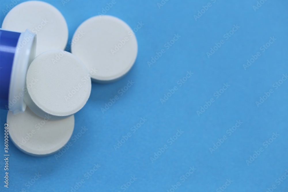 White pills close-up.Cold and flu.Treatment and prevention of viral diseases. Round white pills close-up on a blue background.Medicine and health .Medication and prescription pills. White pills close-up.Cold and flu.Treatment and prevention of viral diseases. Round white pills close-up on a blue background.Medicine and health .Medication and prescription pills.
