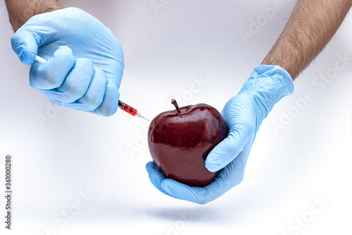 Syringe injection into a apple with sorbic acid waiting for long-term storage of fruit. Genetic modified foods. isolated on white background photo