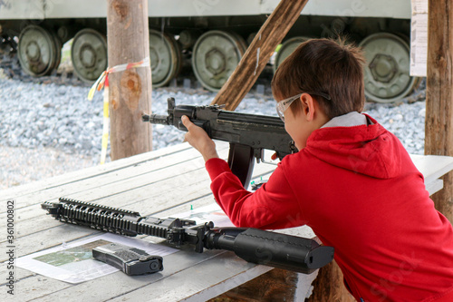 young boy with a machine gun in the outdoor shooting gallery