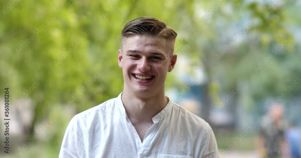 A young man smiles and looks at the camera. Portrait of a happy handsome young man on a city street. Close up face of a young man A young man smiles and looks at the camera. Portrait of a happy handsome young man on a city street. Close up face of a young man