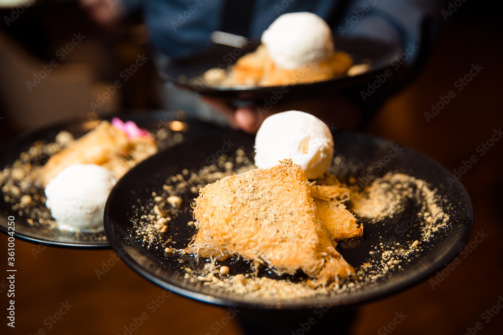 Crispy pastry dessert, melted cheese inside and sprinkled with crushed pistachios. Dessert served with a scoop of white ice cream. Crispy pastry dessert, melted cheese inside and sprinkled with crushed pistachios. Dessert served with a scoop of white ice cream.