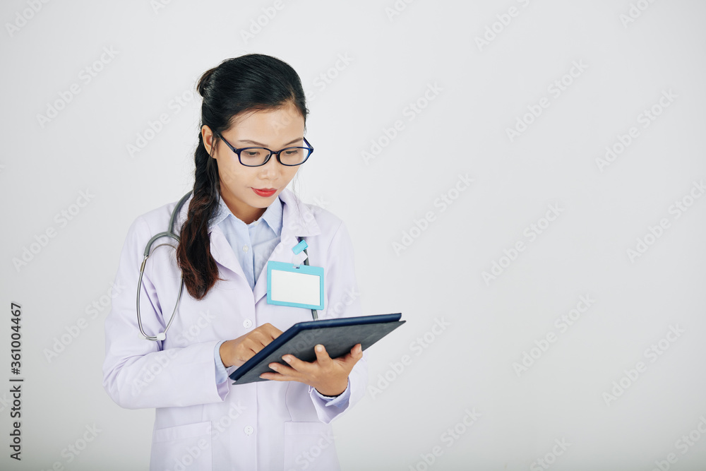 Young Asian medical intern checking infromation on tablet computer, isolated on white Young Asian medical intern checking infromation on tablet computer, isolated on white