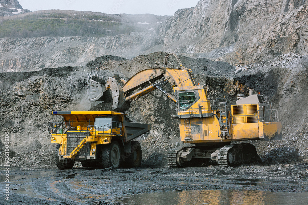 Excavator loads ore into a mining dump truck. Excavator loads ore into a mining dump truck.
