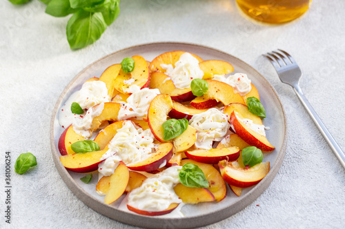 Fresh salad with peaches, Italian Stracciatella cheese, Basil, olive oil and honey. Summer salad, healthy food concept. Selective focus