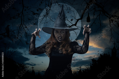 Scary halloween witch standing over cross, church, crow, bat, birds, dead tree, full moon and sunset sky, Halloween mystery concept