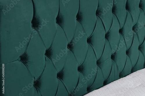 Closeup shot of a bed with green fabric headboard and white mattress photo