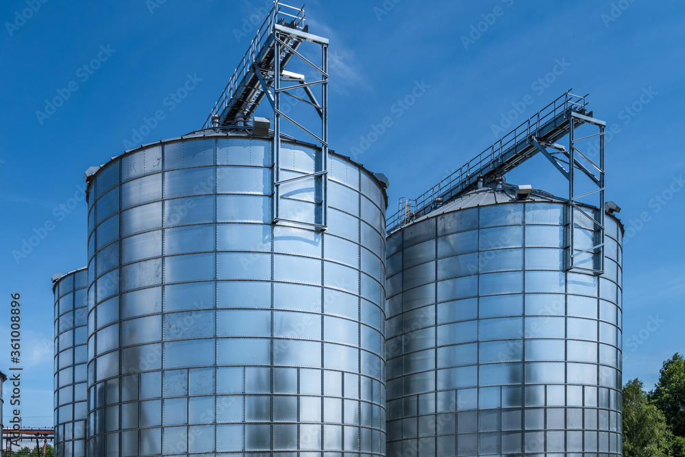 silver silos on agro-processing and manufacturing plant for processing drying cleaning and storage of agricultural products, flour, cereals and grain. Granary elevator.