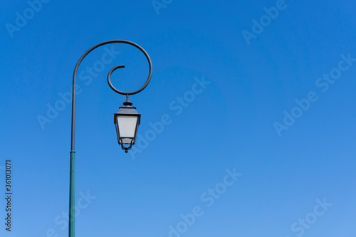 Vintage polelight, white glass and black body lamp on black steel with circle on the top, under deep blue sky background photo