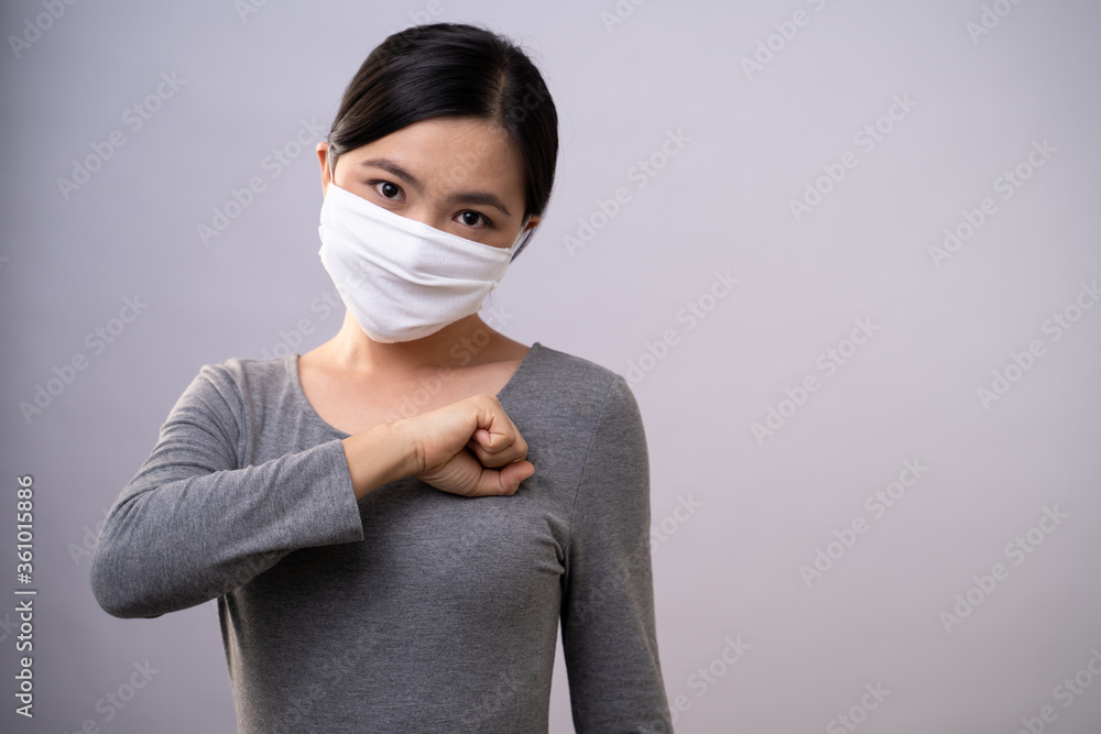 Asian woman wearing protective face mask put her fist on a left chest isolated on background. Asian woman wearing protective face mask put her fist on a left chest isolated on background.
