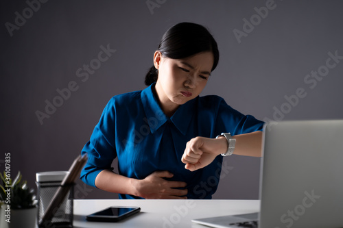 Asian woman in blue shirt was sick with stomach ache sitting at office. isolated on white background.